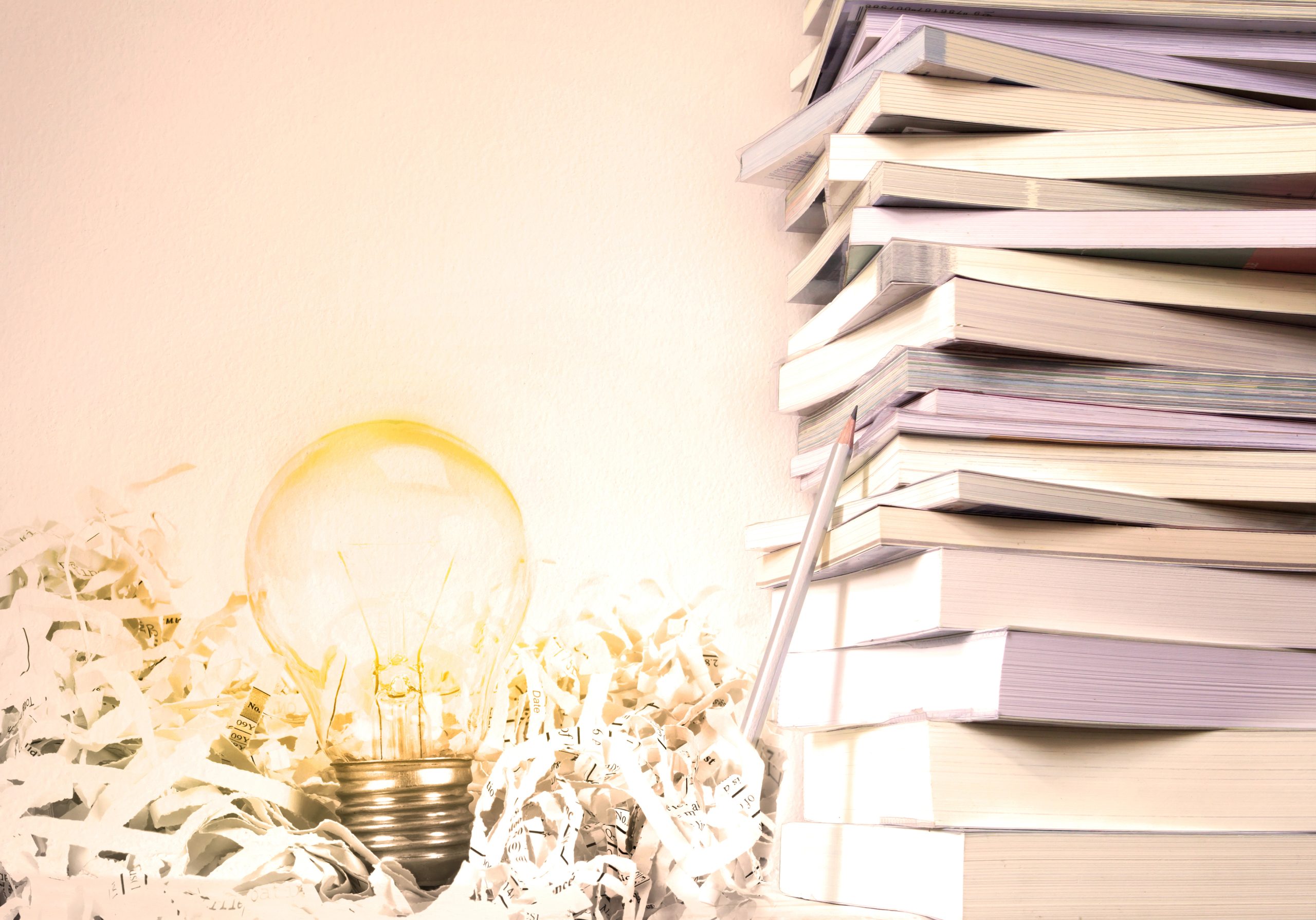 Close,Up,Book,Stacked,With,The,Glowing,Light,Bulb,Background
